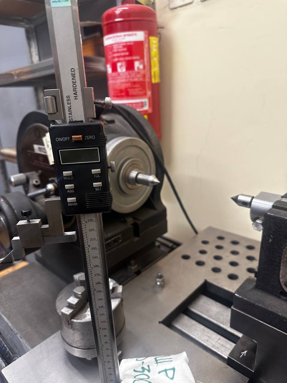 A digital height gauge on a surface plate, with a part set up between centres.